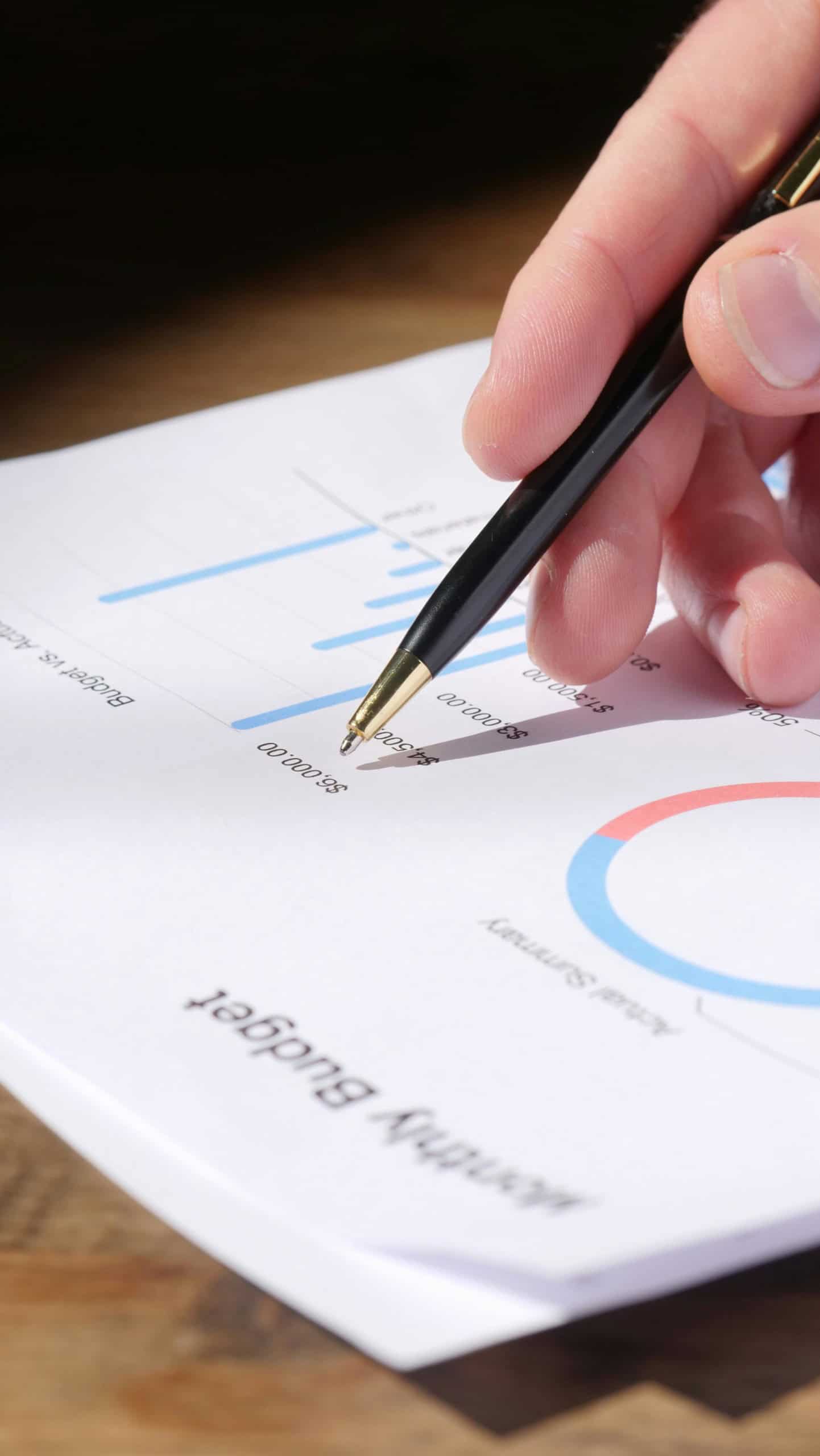 Person tracking budget with pen and paper.